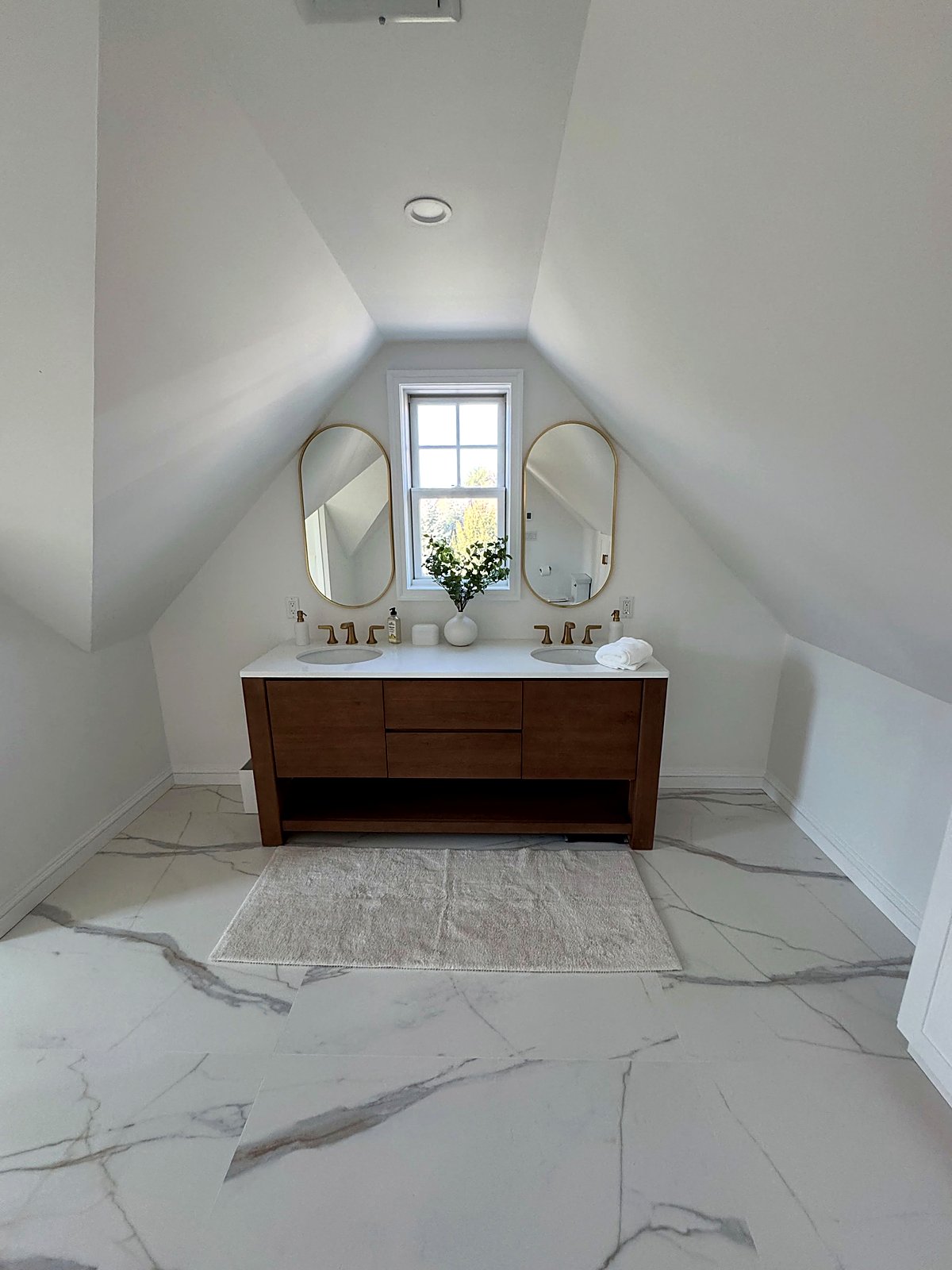 Attic bathroom with a walnut double vanity under a sloped ceiling