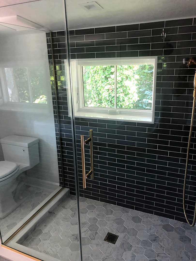 Walk-in shower with black subway tile, a gray hex tile floor, and a window