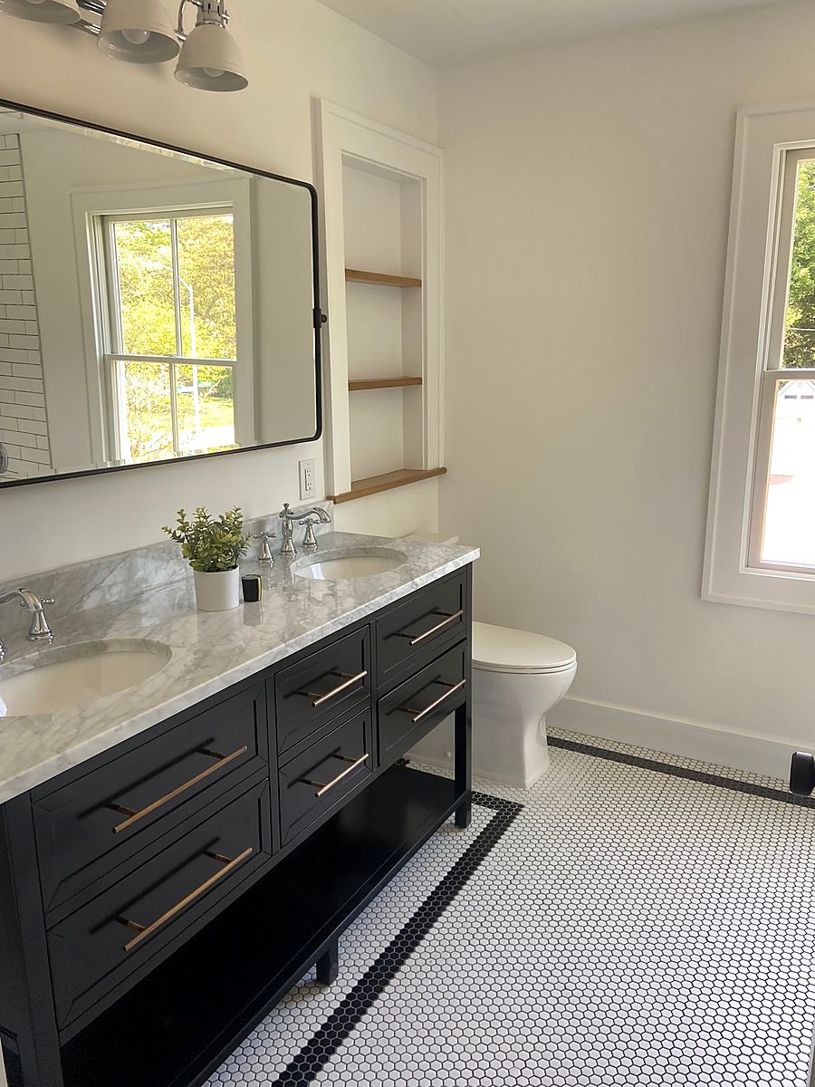Navy double vanity with marble counters set between two windows