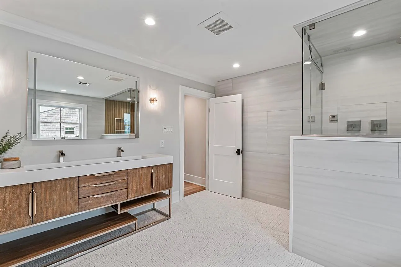 Bathroom with a floating walnut double vanity, a trough sink, and a walk-in shower