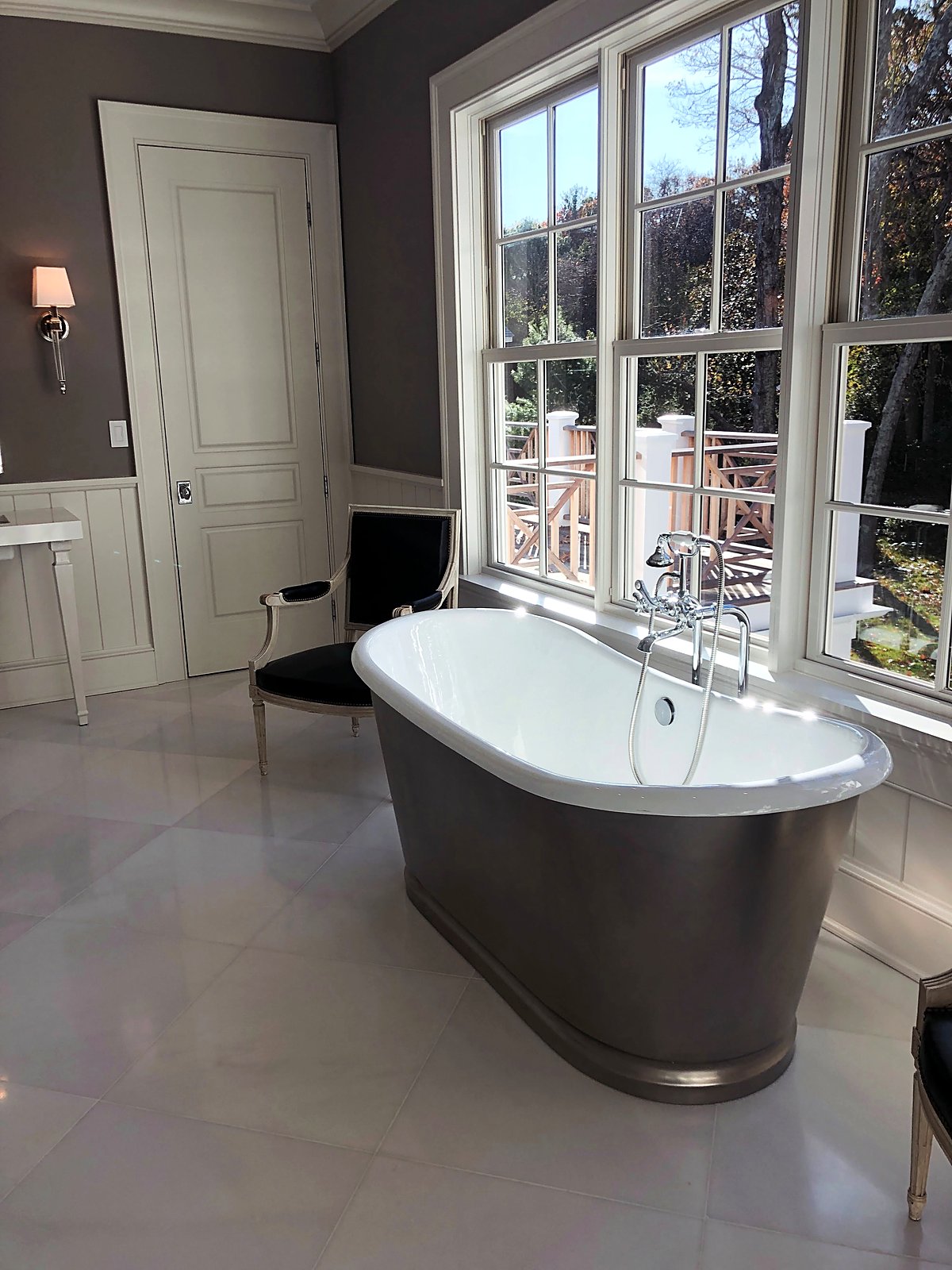 Primary bathroom with a freestanding soaking tub beneath a wall of windows
