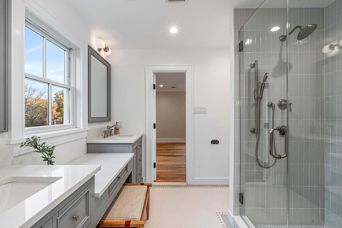 Bathroom with a gray double vanity, a glass shower, and a marble mosaic floor