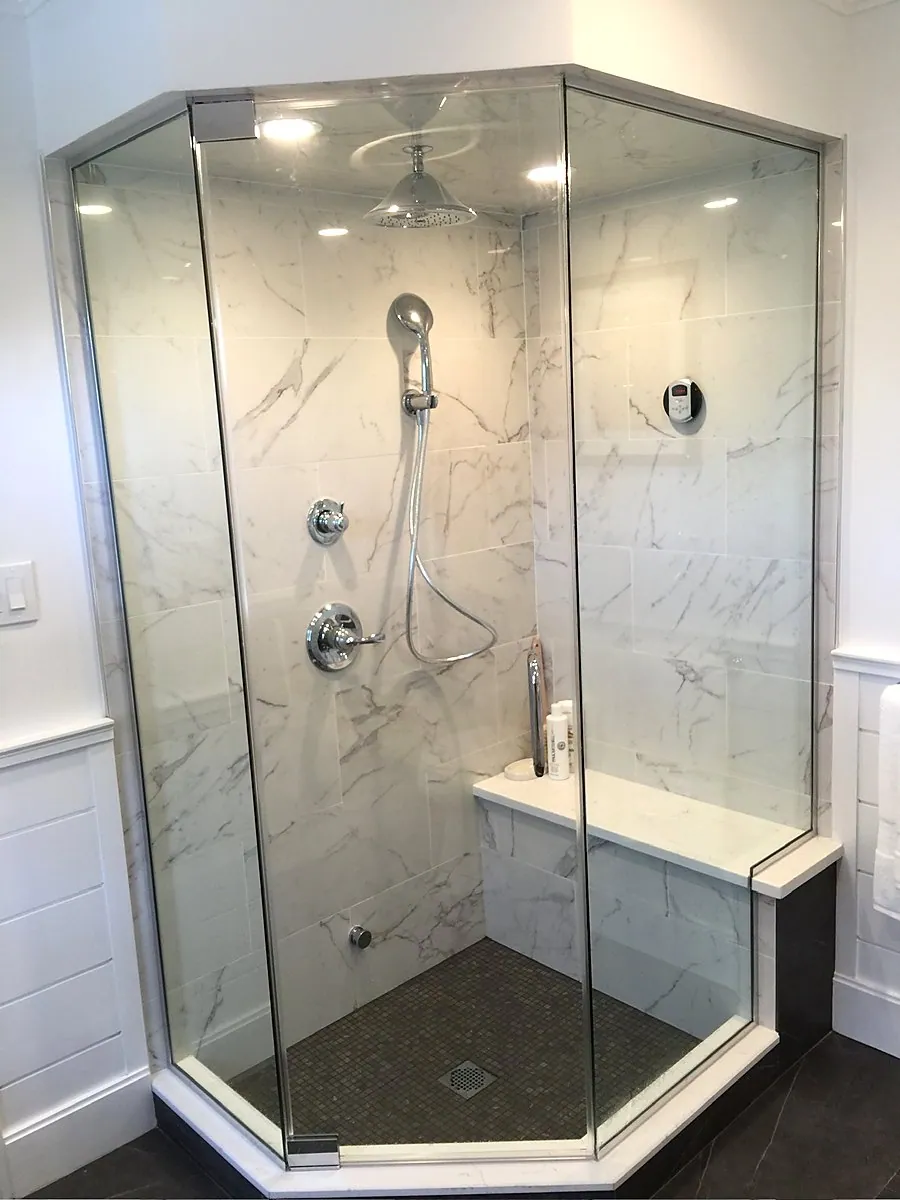 Neo angle glass shower framed in marble tile with a built-in bench