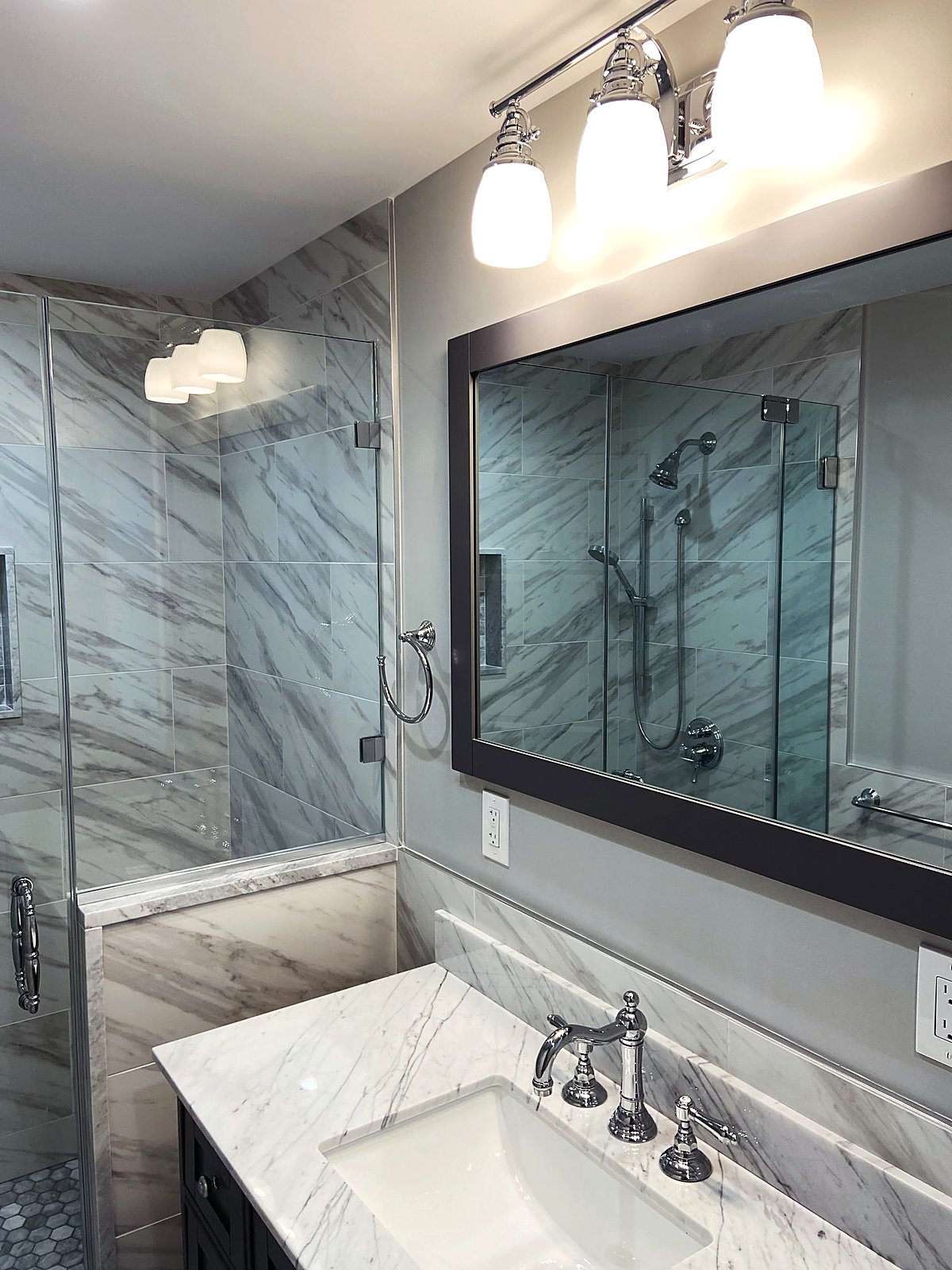 Marble tiled bathroom with a dark framed mirror and a marble vanity top
