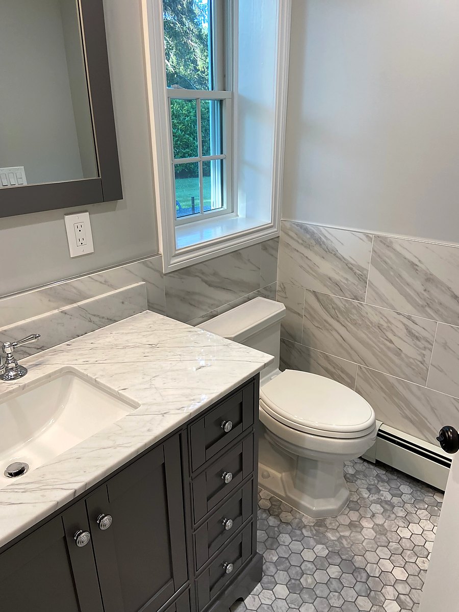 Bathroom with a dark wood vanity, marble counter, and a hexagon tile floor