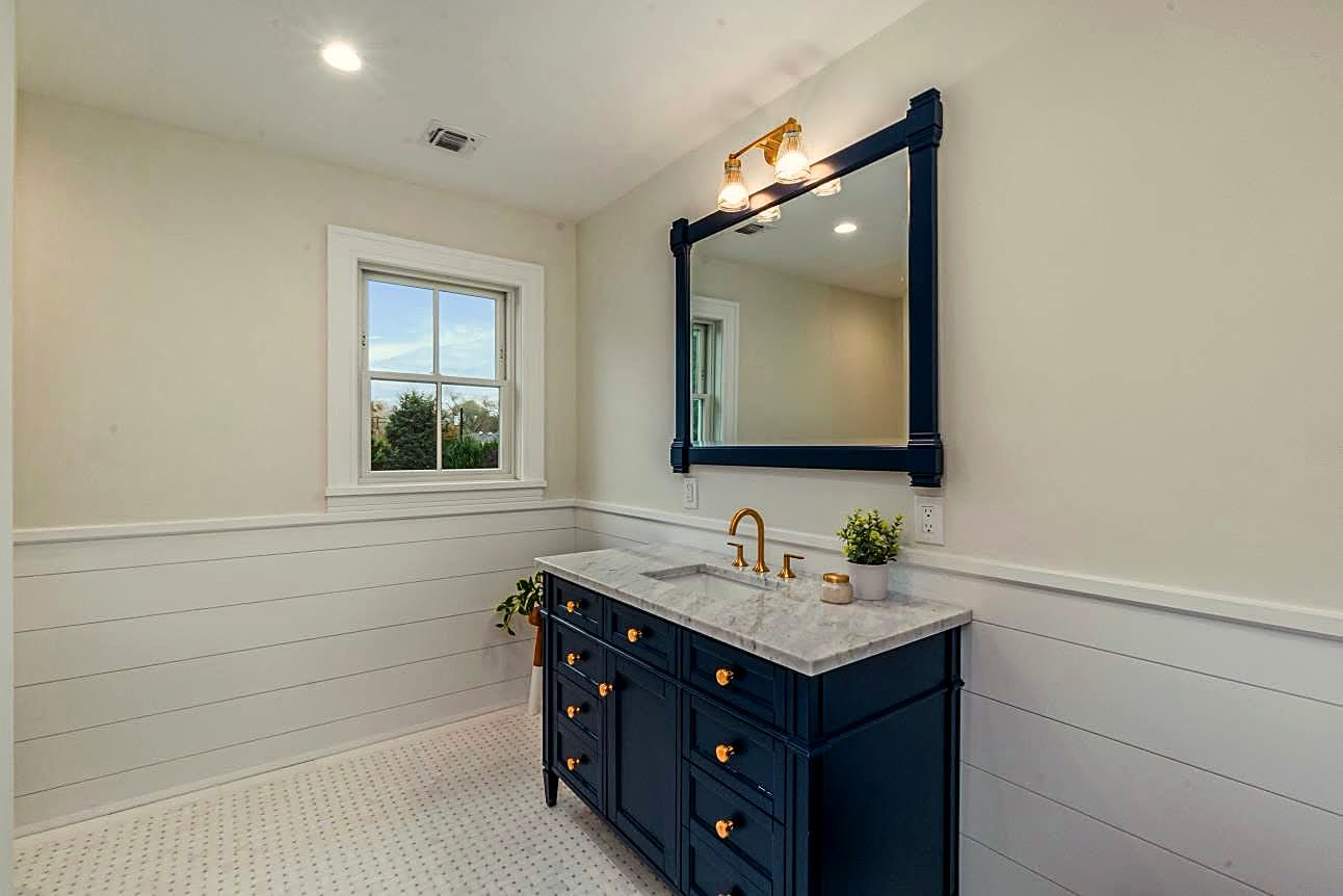 Bathroom with a navy vanity, brass hardware, and white shiplap wainscoting