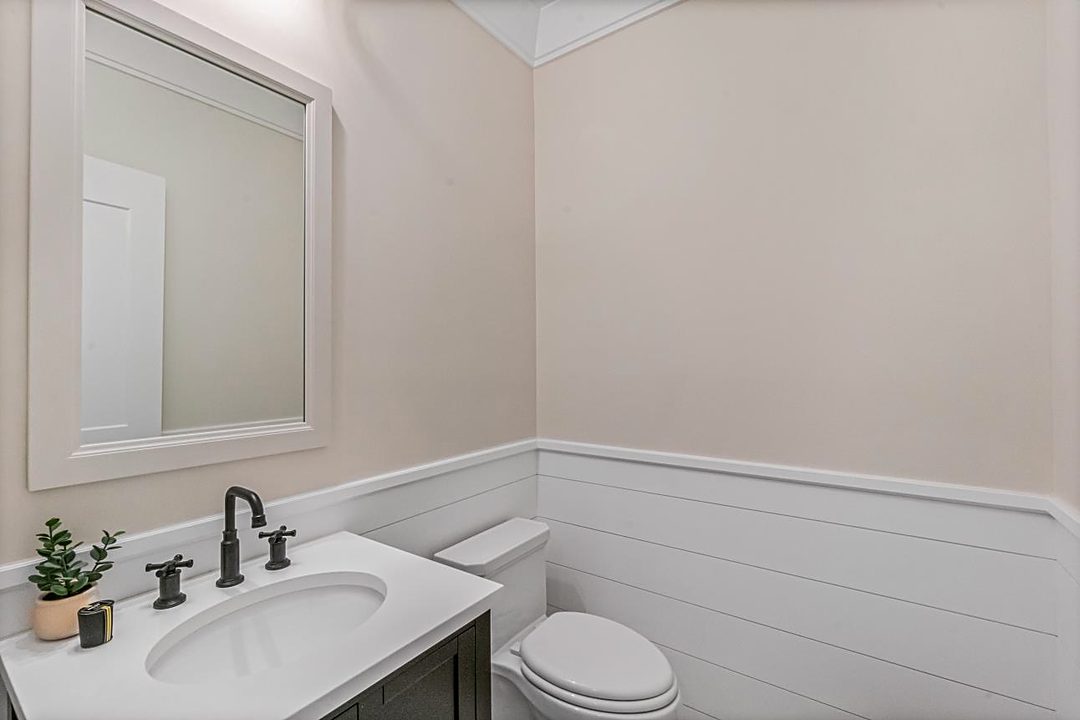 Powder room with a white vanity, a black faucet, and shiplap wainscoting
