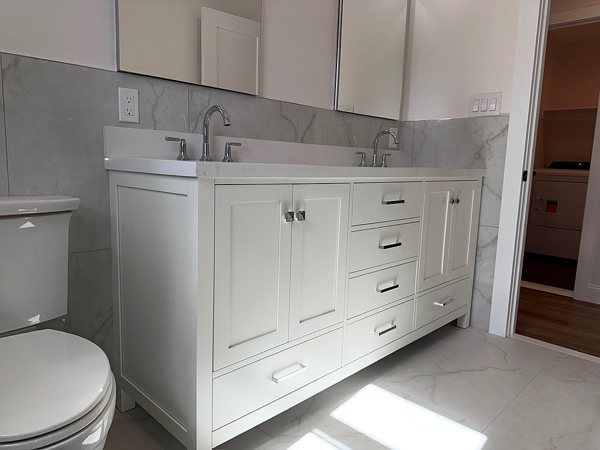 White double vanity with quartz counters beside a tiled shower
