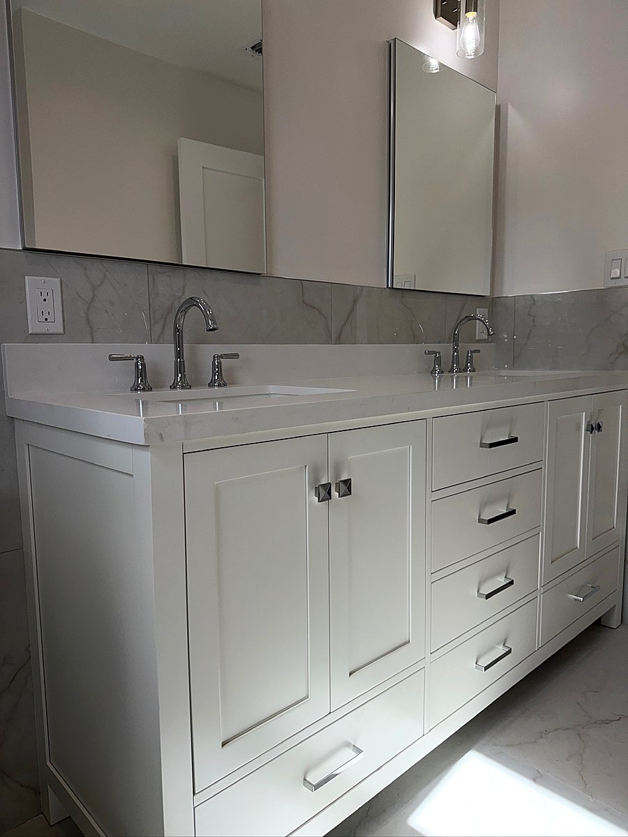 White double vanity with a wide mirror and marble wall tile