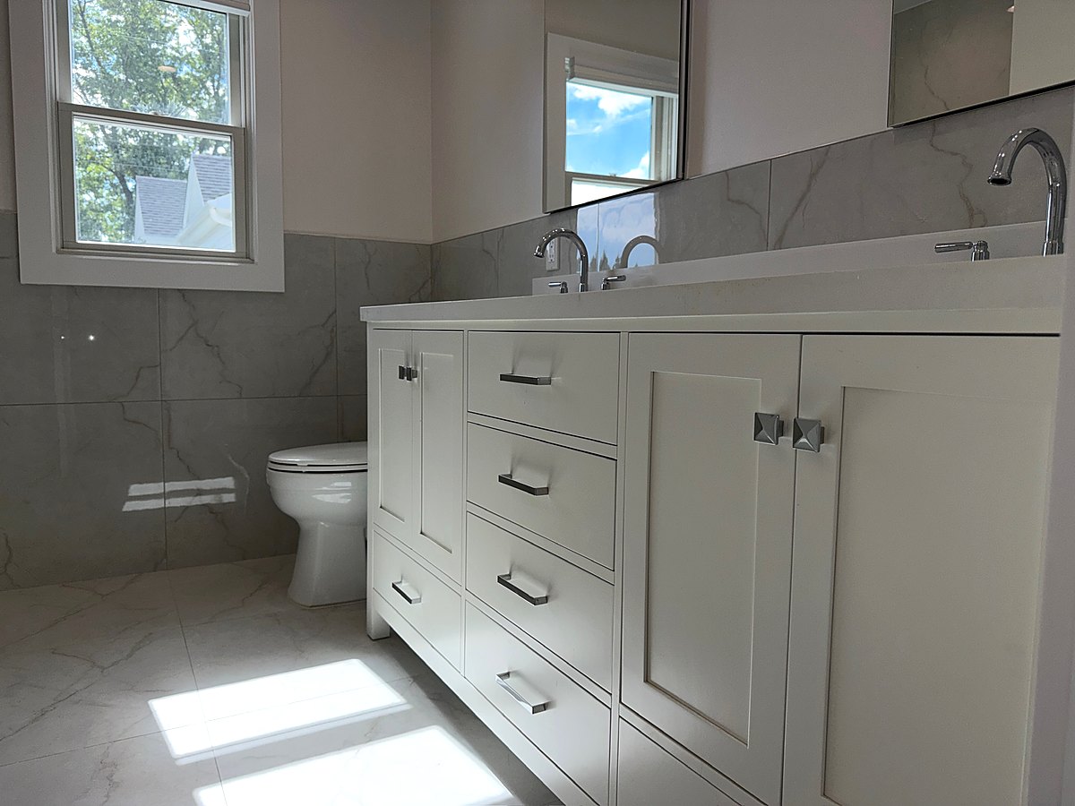 Bathroom with a white vanity, marble wall tile, and a tub shower surround