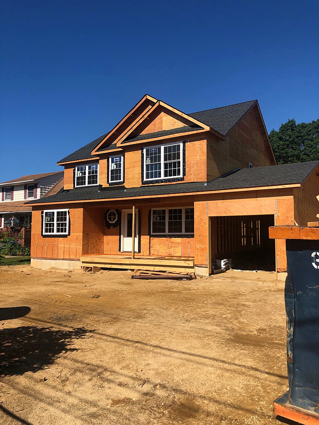 Sheathed: Sheathed and shingled, with windows installed and the front porch deck framed.