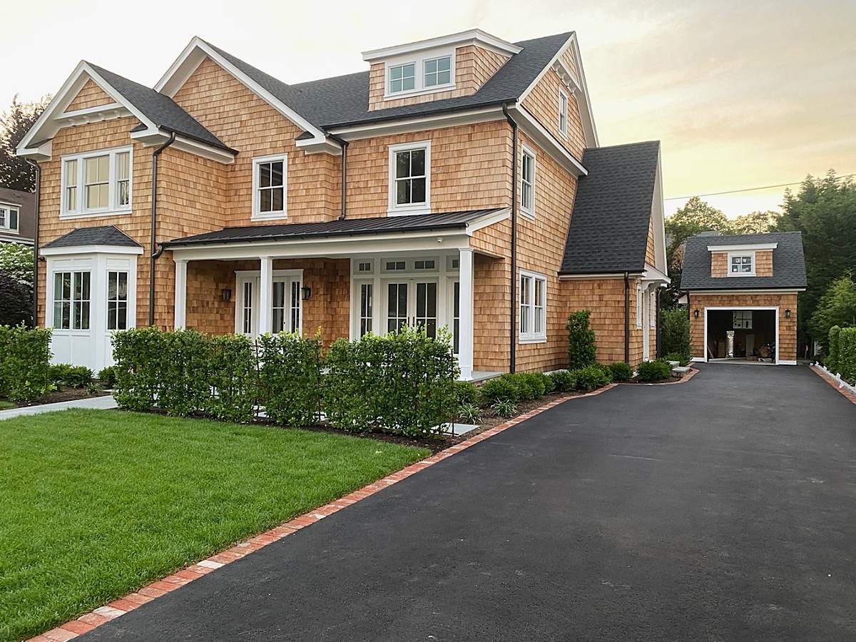 Cedar shake shingled custom home with white trim, a paver walkway, and a detached garage