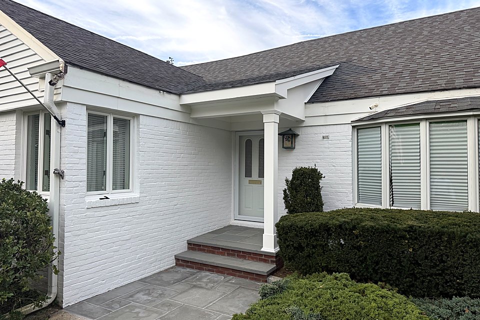 Finished: White portico over the front door with a square column and a bluestone walk.