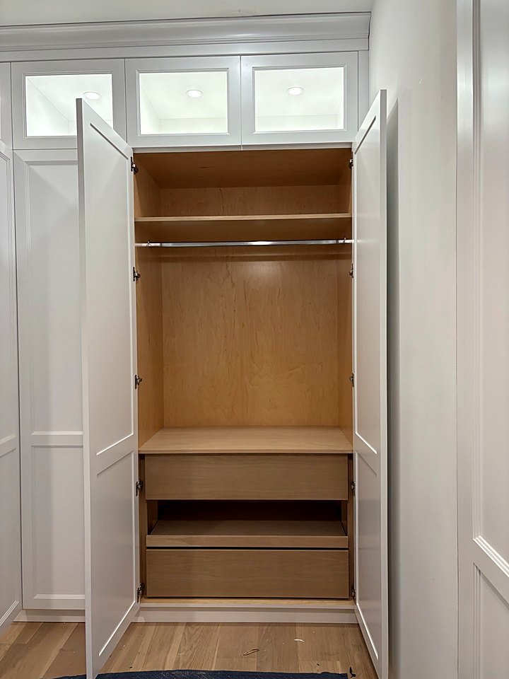 Built-in white wardrobe opened to show oak shelving and drawers