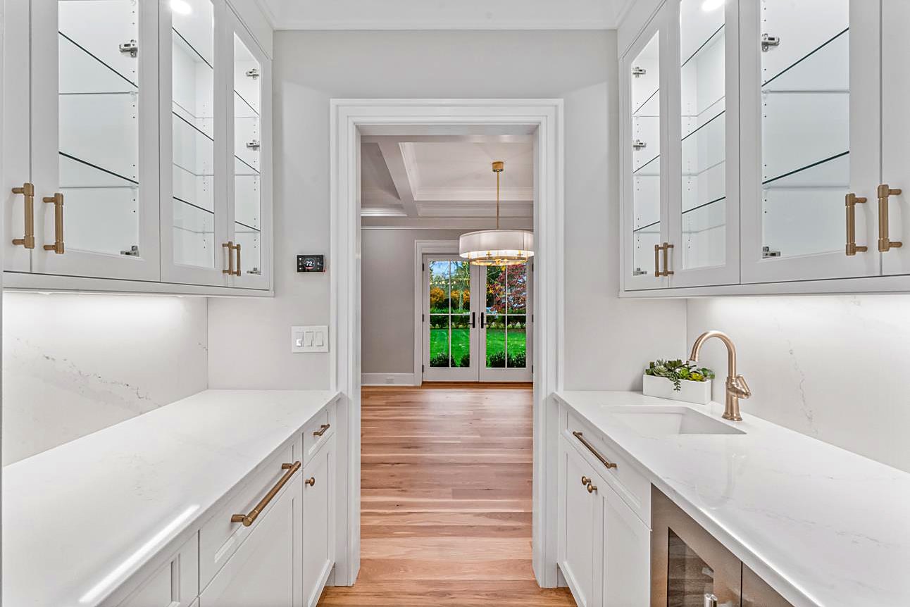 Butler's pantry with mirrored upper cabinets, quartz counters, and a prep sink