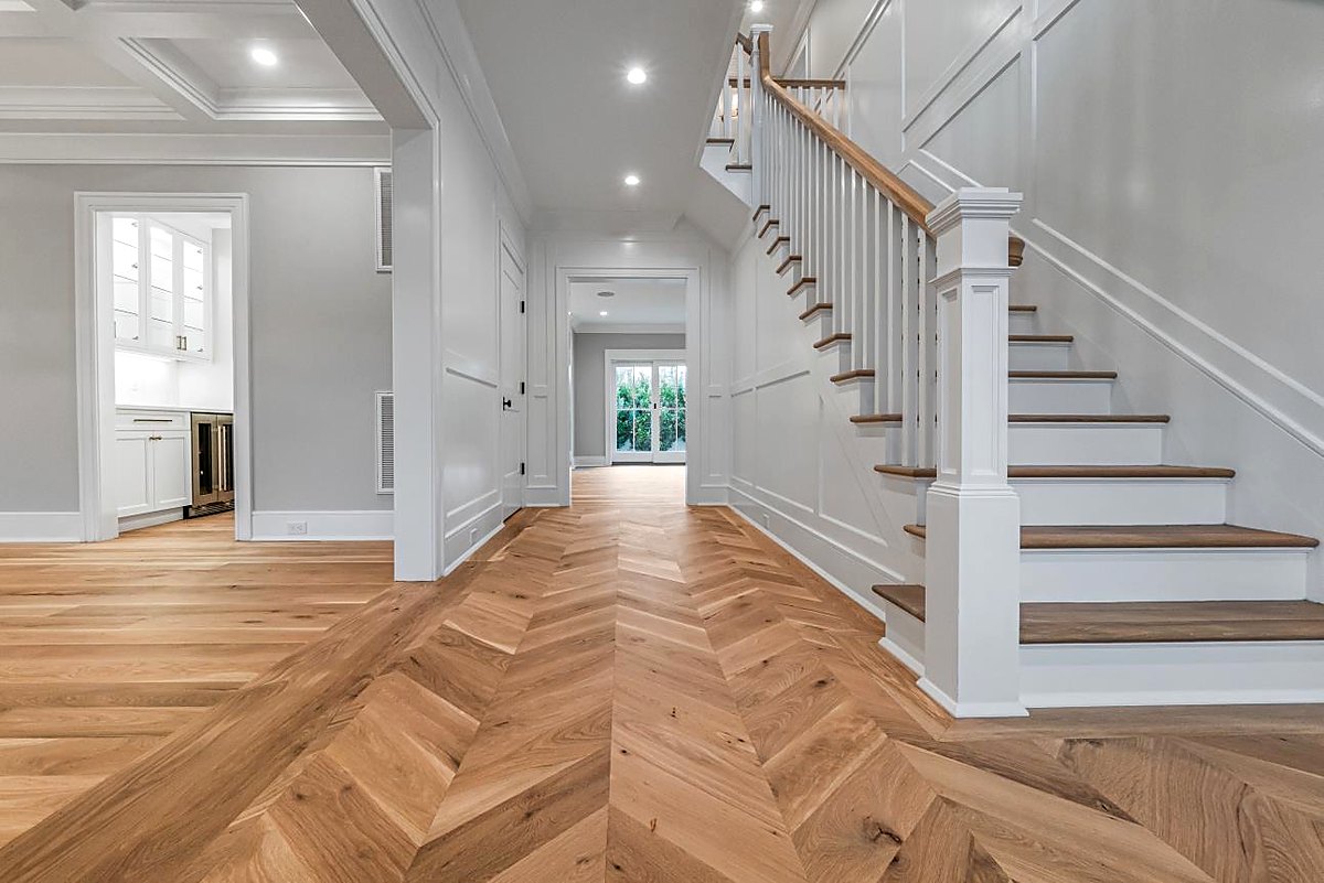 Hallway with herringbone floors leading to the main staircase