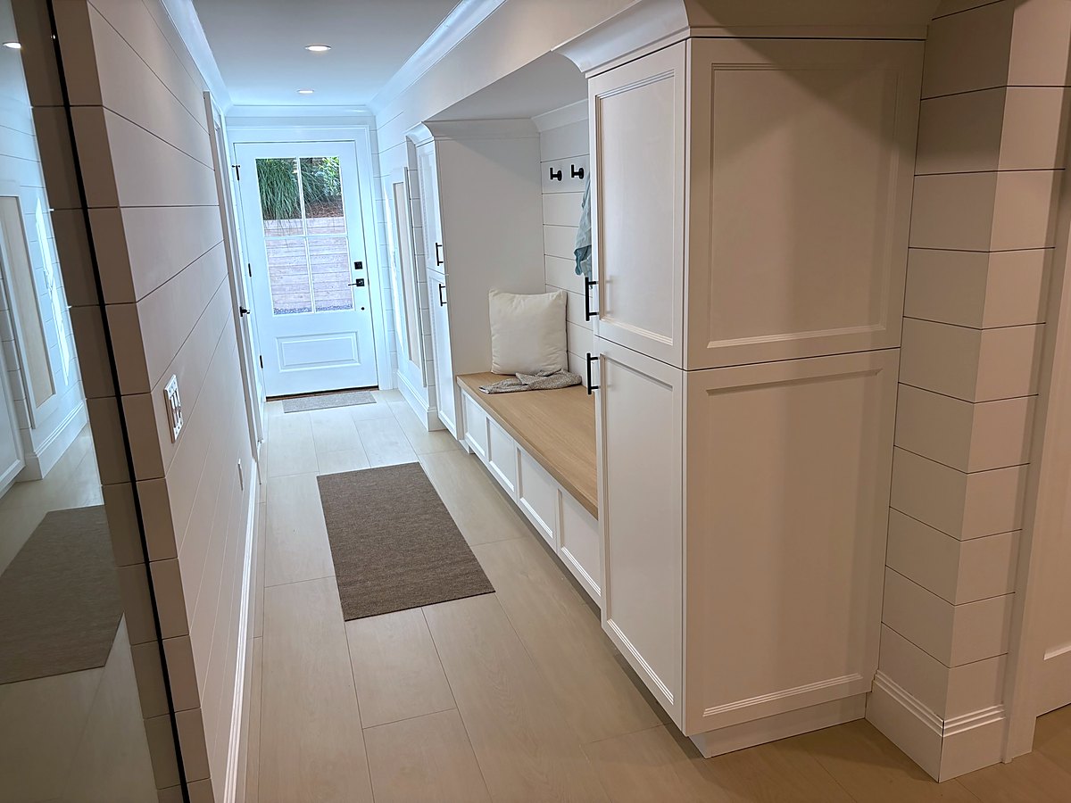 Hallway lined with custom white built-in cabinetry and a bench