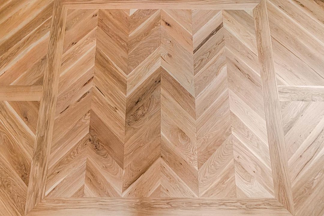 White oak herringbone floor inlay framed by a border of straight boards
