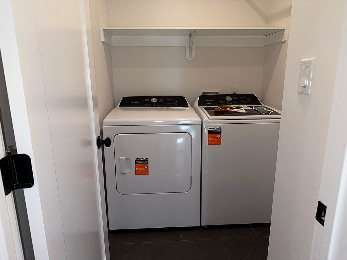 Laundry room with a washer and dryer set beneath open shelving