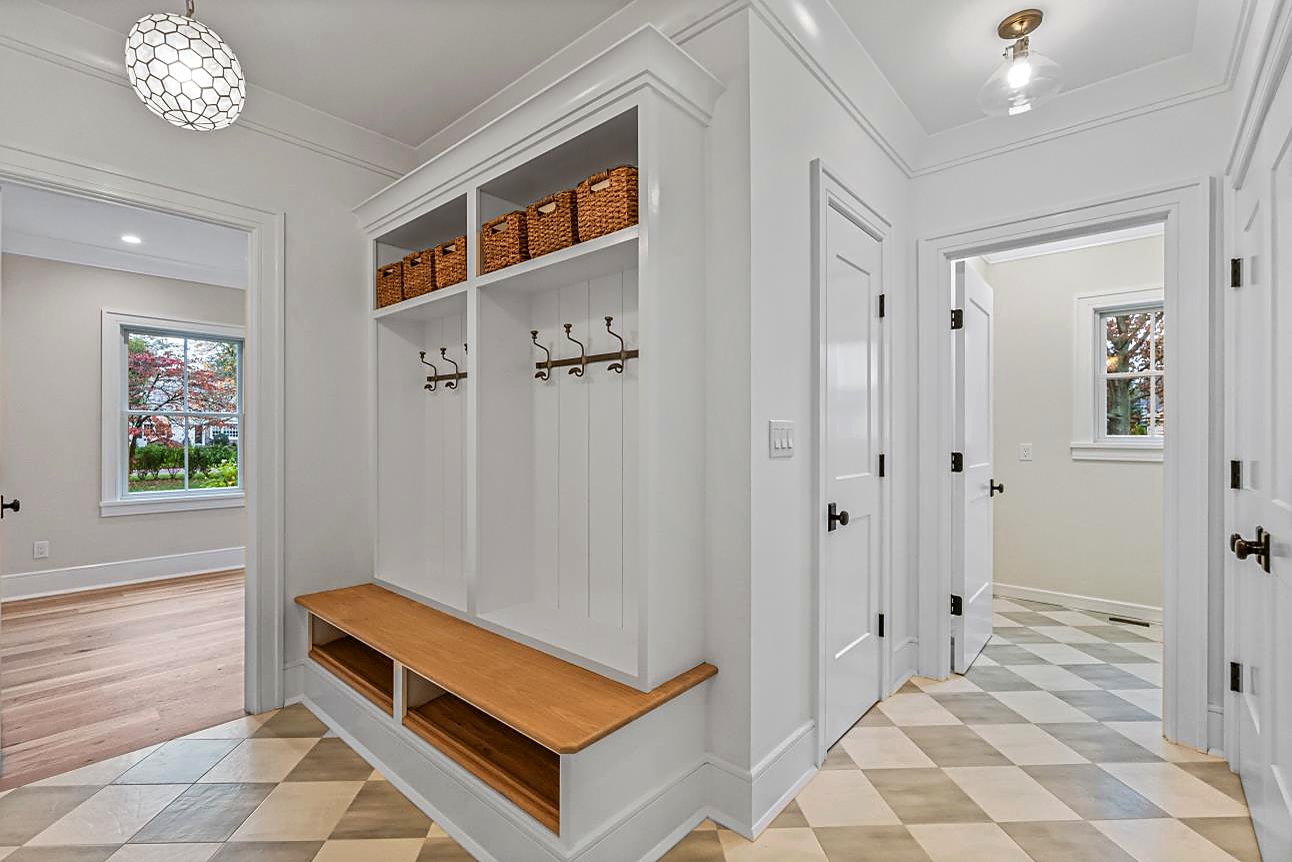 Mudroom with a built-in bench, woven storage baskets, and a checkerboard tile floor
