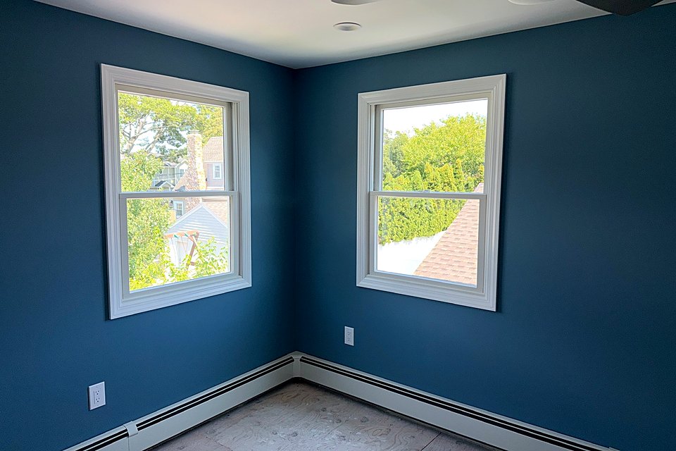 Bedroom painted deep navy with two new windows and white trim