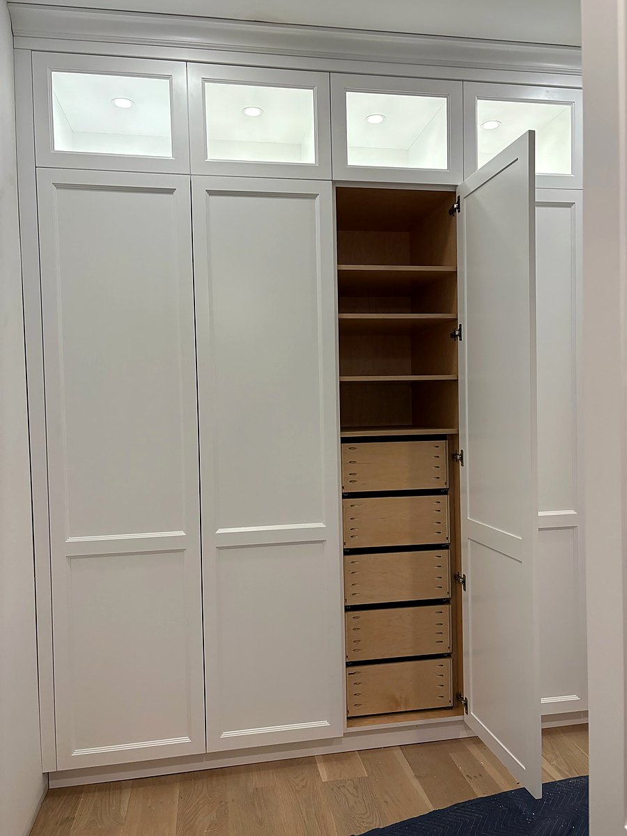 White oak closet shelving below a run of transom windows
