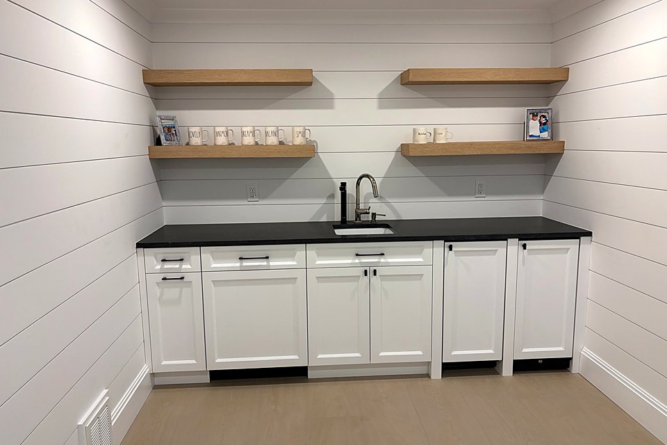 Bar area with white shiplap, floating wood shelves, and black counters