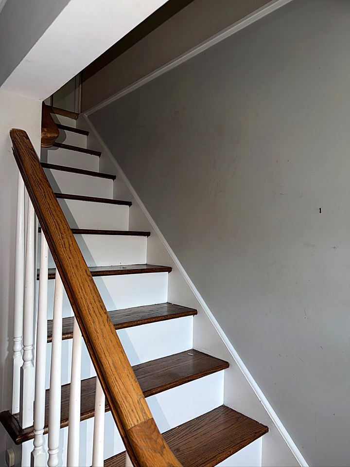 Staircase with stained oak treads, white risers, and a wood handrail