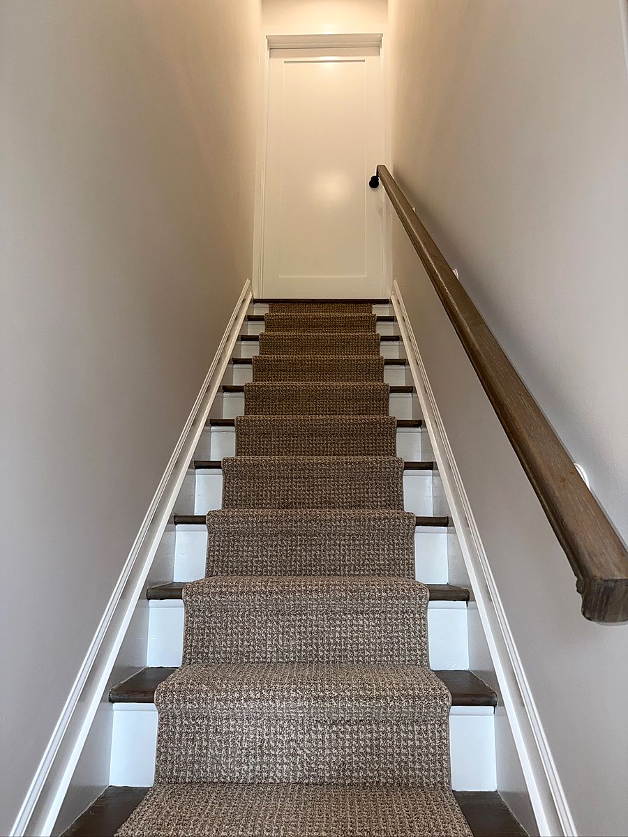 Staircase with a patterned runner and a stained handrail