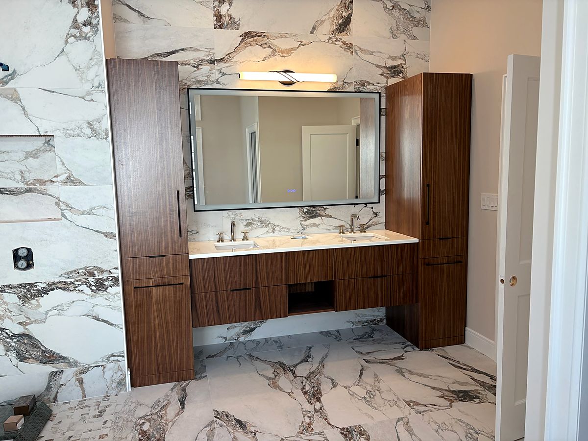Floating walnut vanity against a bookmatched marble slab wall