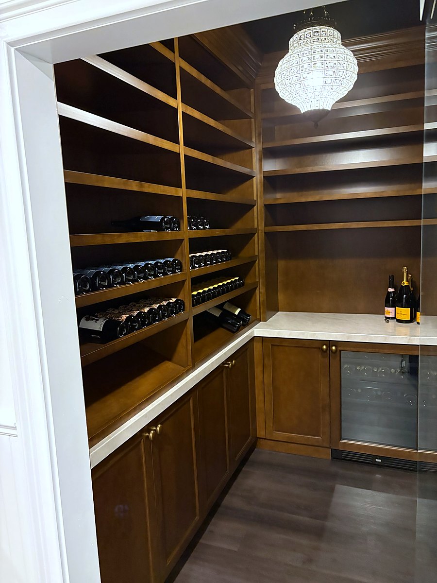 Wine room with oak bottle racking, a glass door cooler, and a pendant light