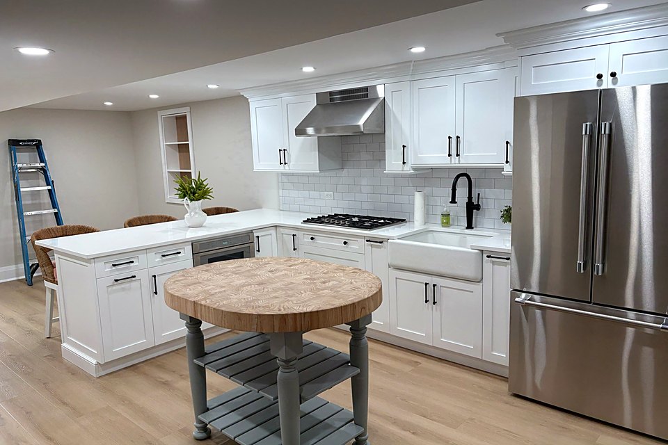 Open white kitchen with an island, a round butcher block table, and stainless appliances