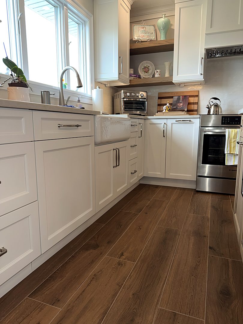 Kitchen sink run with white shaker cabinets and wide-plank hardwood flooring