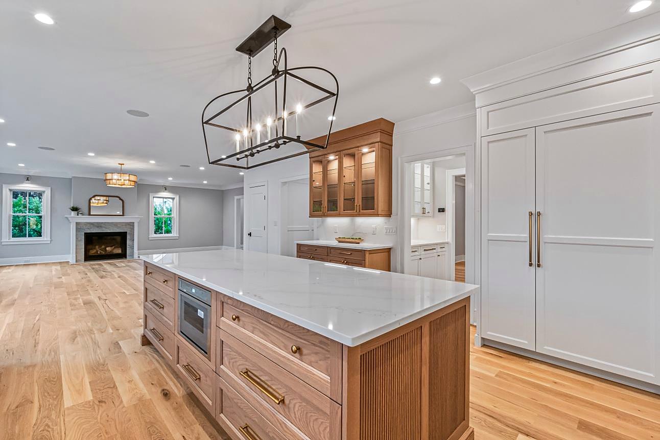 Kitchen island with a marble waterfall counter, a built-in microwave, and brass hardware