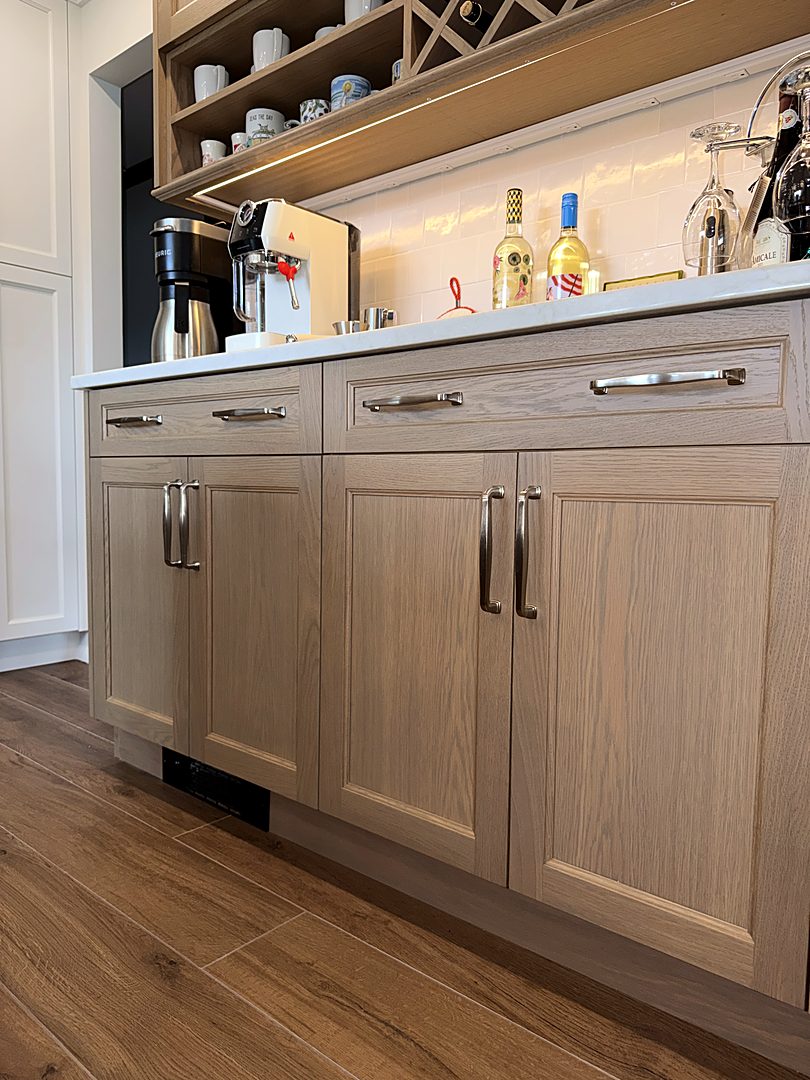 White oak beverage bar with quartz counters, glass storage, and under-cabinet lighting