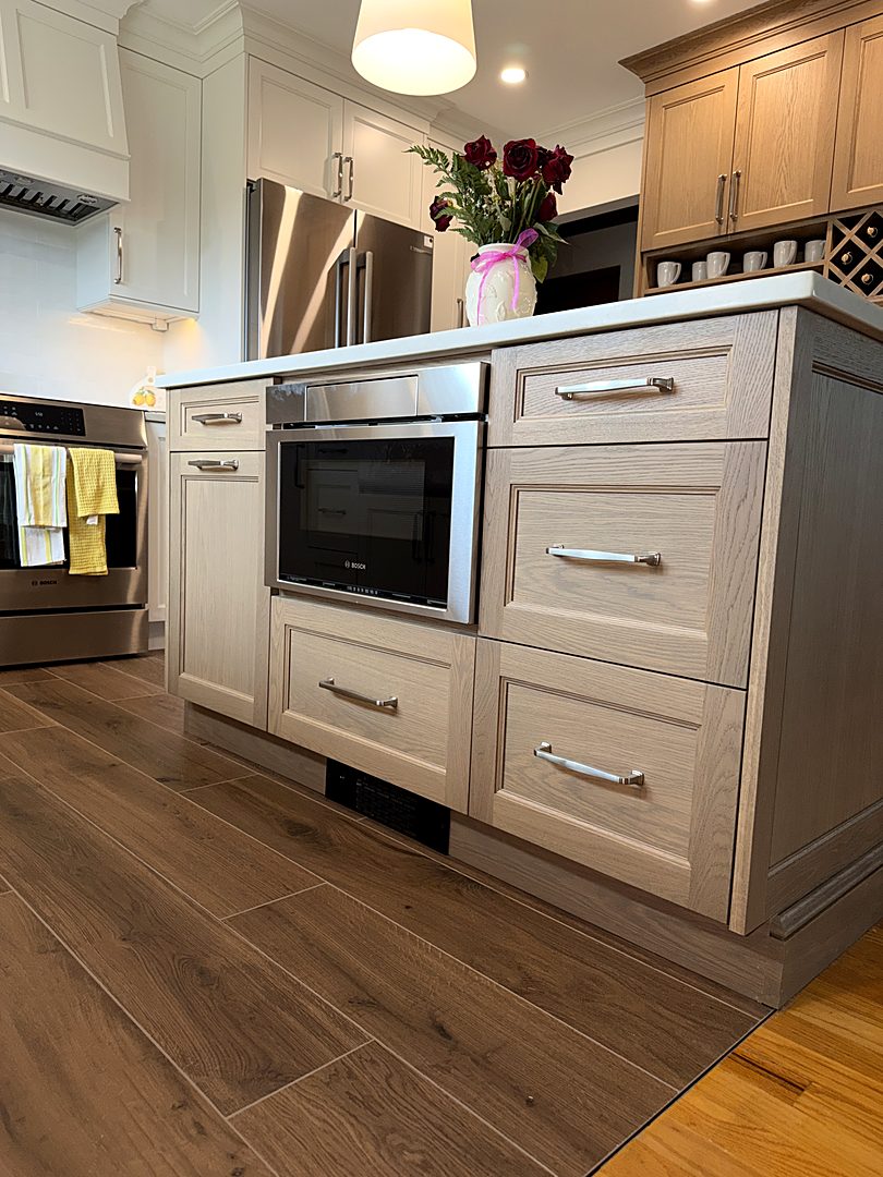 White oak kitchen island with a built-in microwave drawer and brushed nickel hardware