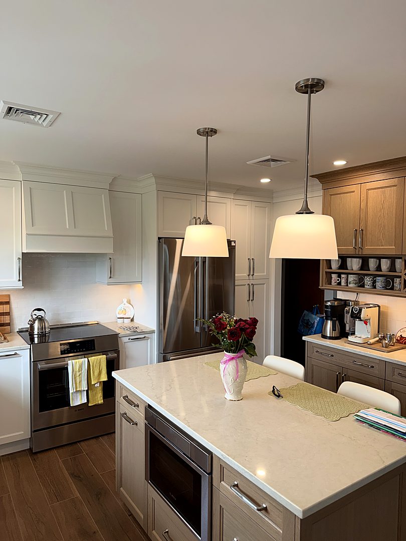 White shaker kitchen with a white oak island, twin pendant lights, and stainless appliances