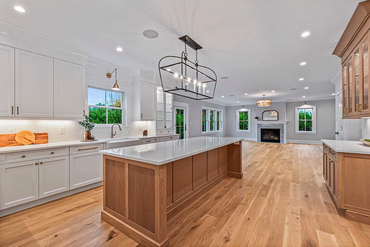 Kitchen open to the great room with a fluted walnut island and a lantern pendant
