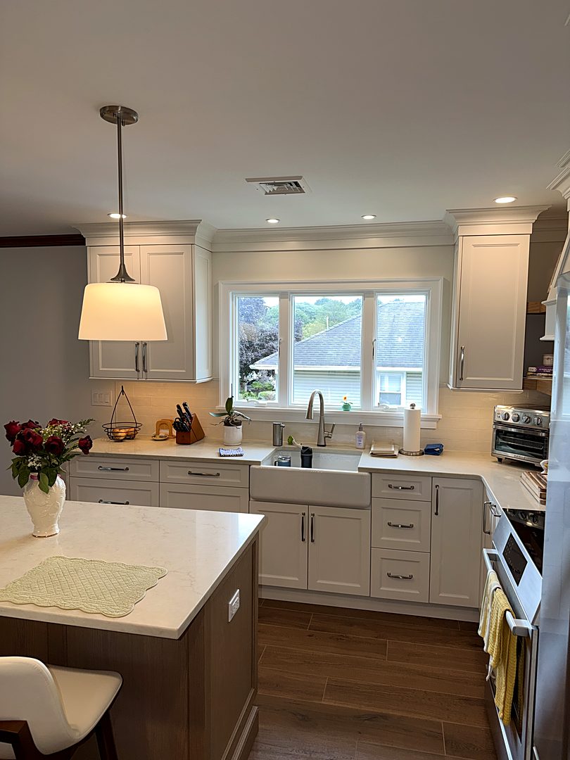 Kitchen island with pendant lighting beneath a wide window over the farmhouse sink