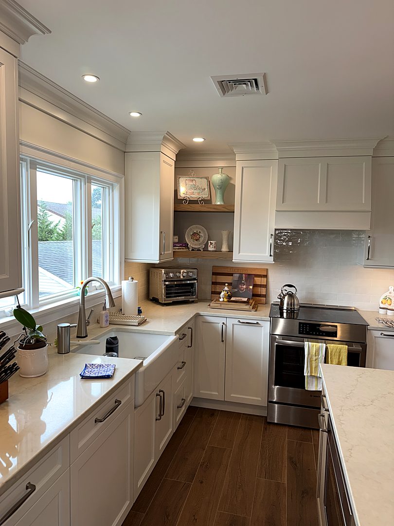 White kitchen with a farmhouse sink, corner open shelving, and a stainless range