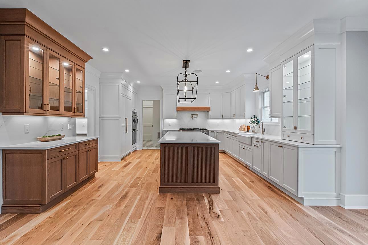Kitchen with white perimeter cabinets, a walnut island, and a marble backsplash