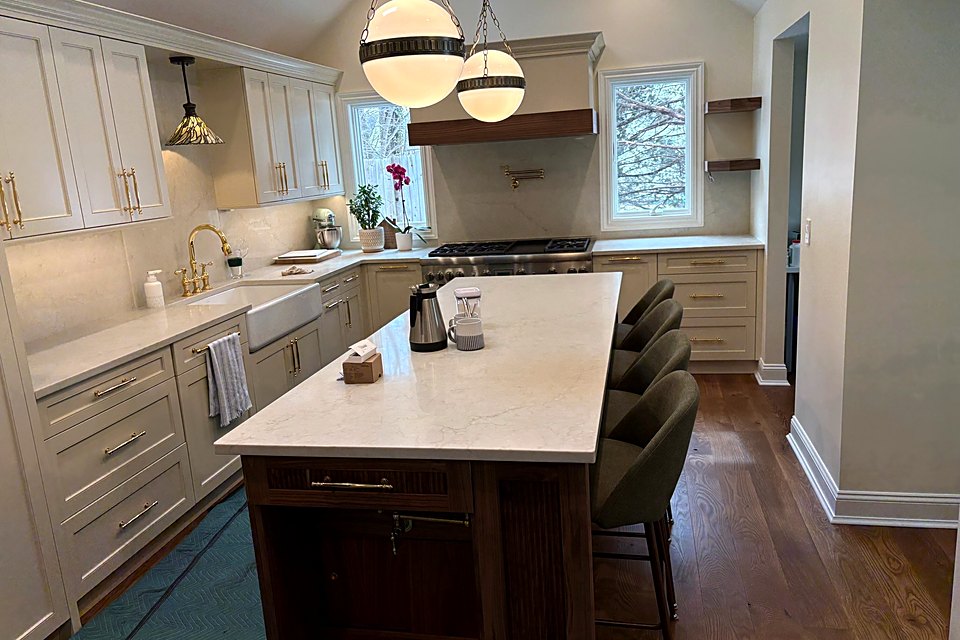 Long kitchen with a walnut island, white quartz, and globe pendant lights