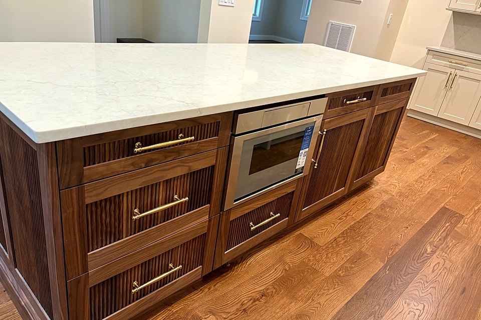 Walnut island with a built-in microwave drawer and a white quartz top