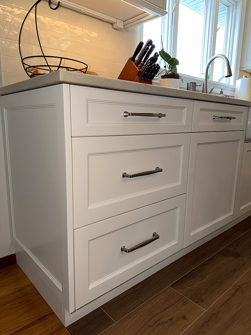 White shaker drawer bank with brushed nickel pulls and a quartz countertop