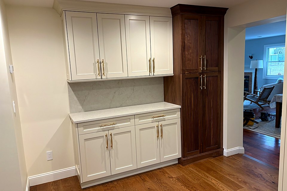 White hutch cabinets beside a tall walnut pantry cabinet