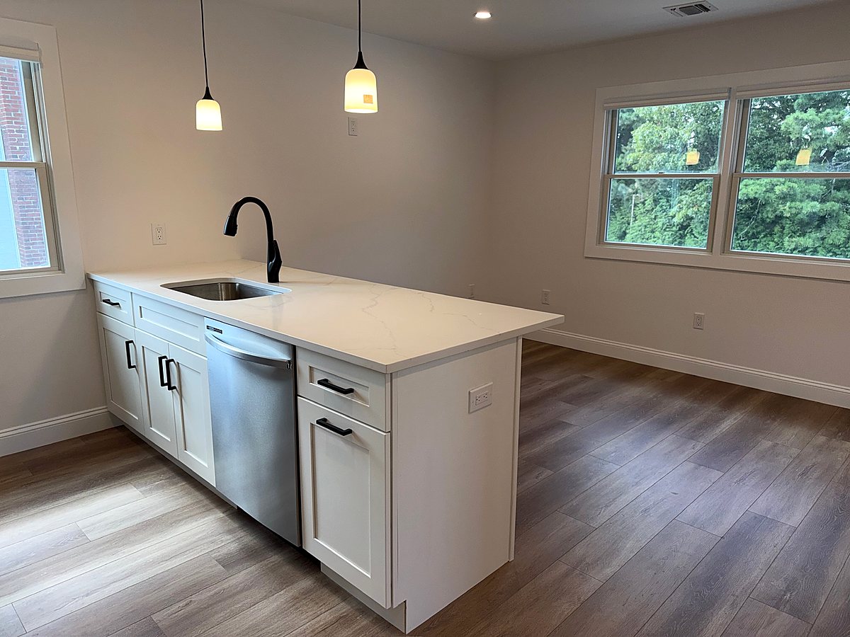 White kitchen island with a quartz top and a matte black faucet