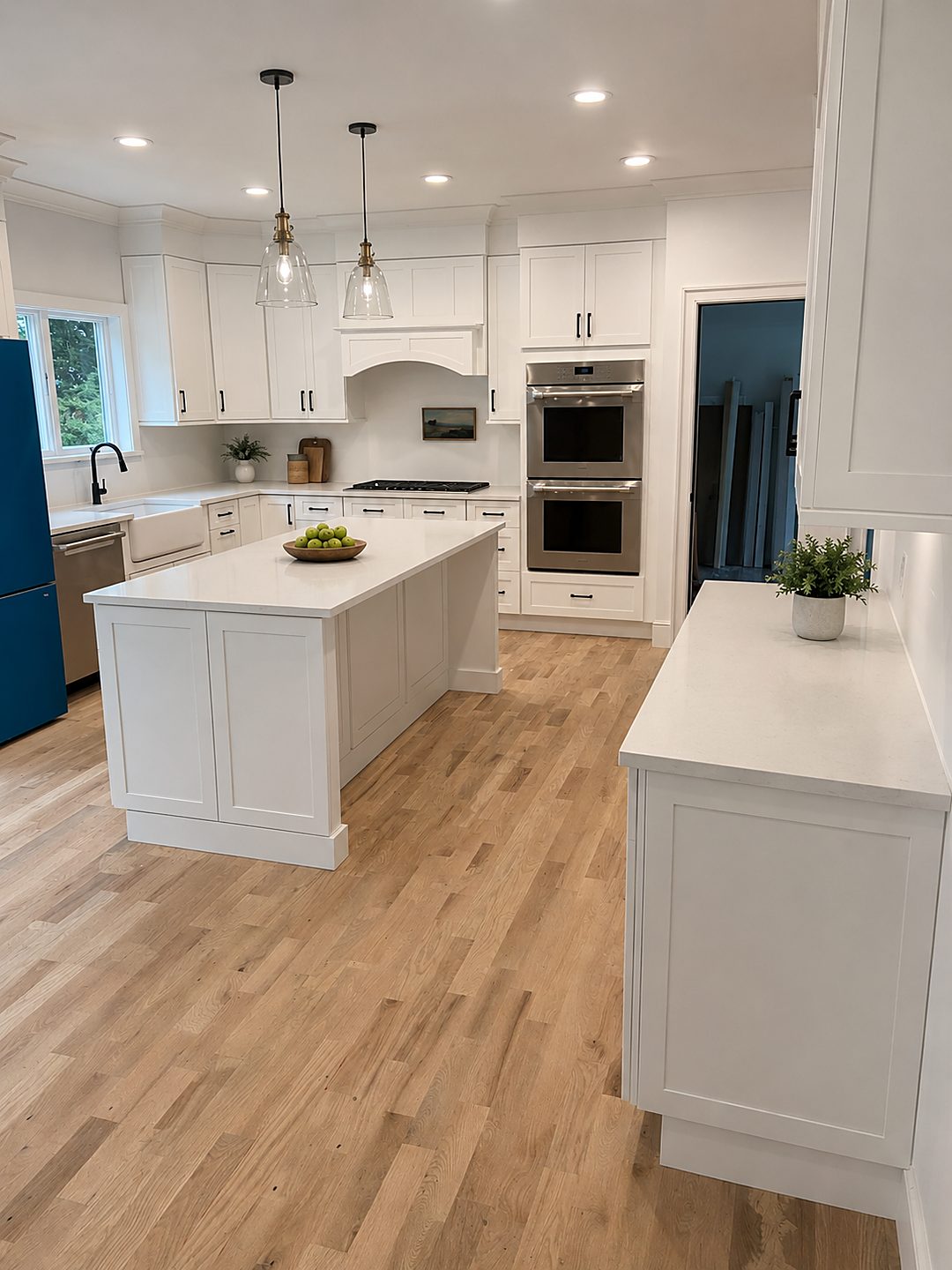 White shaker kitchen with a large island, farmhouse sink, and white oak flooring