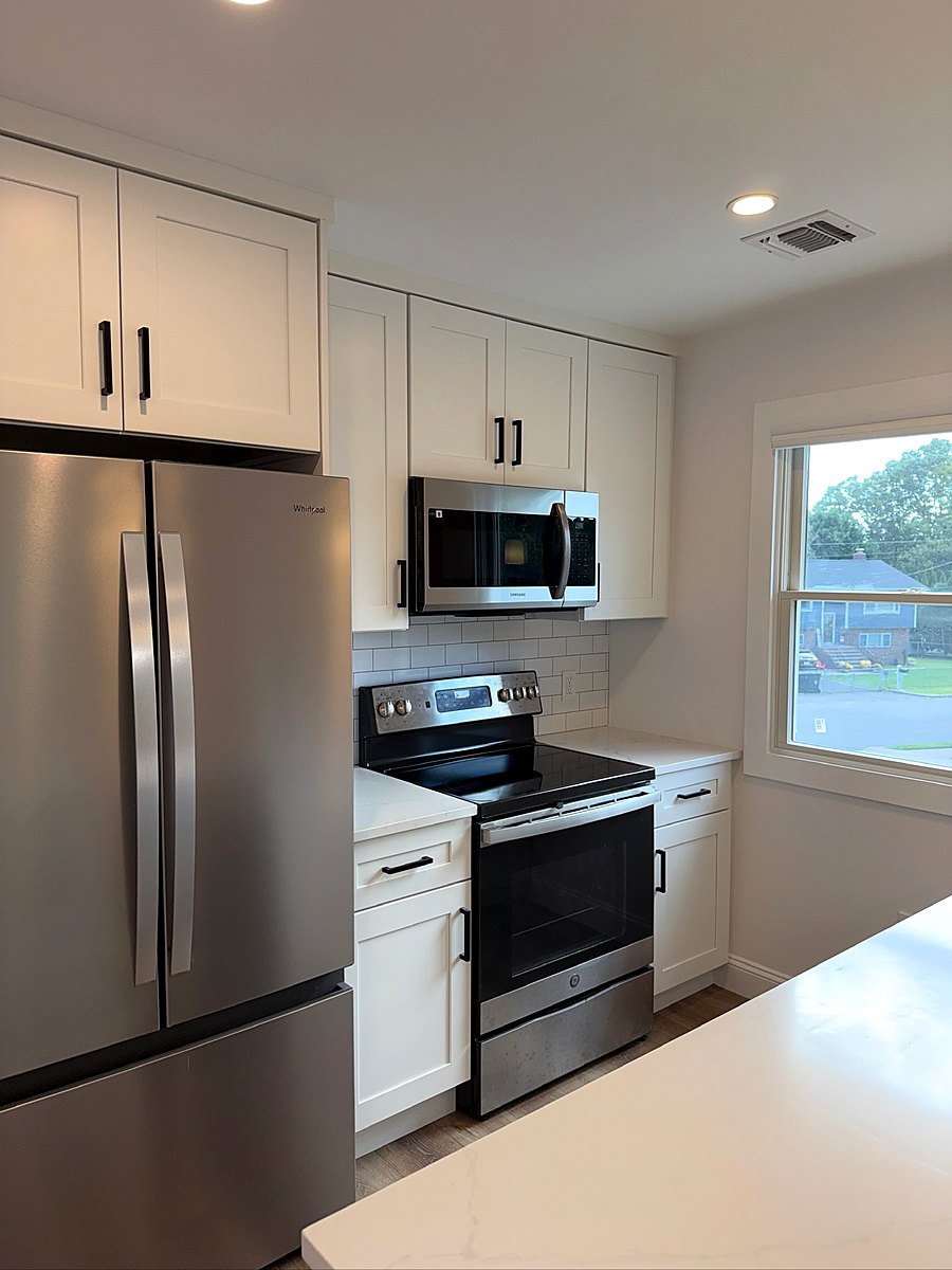 White shaker kitchen with a stainless range, microwave, and refrigerator