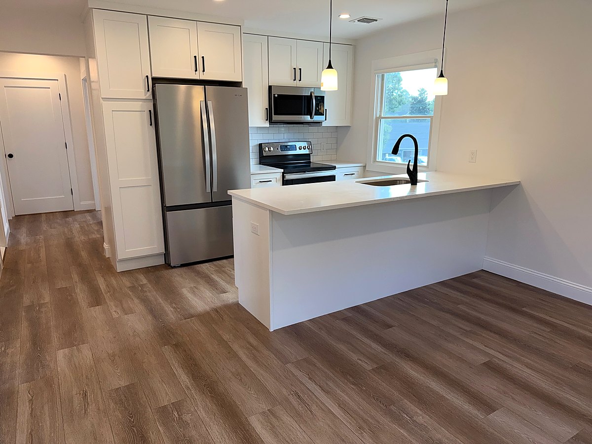 White shaker kitchen with stainless appliances and a quartz island