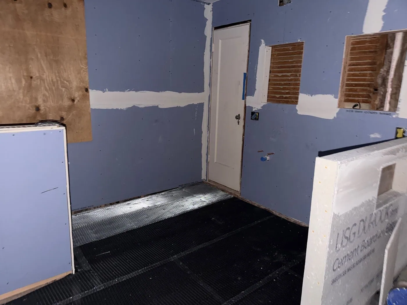 Walls boarded: Blue moisture resistant board on the walls, USG Durock cement board on the half wall, and black underlayment on the floor.